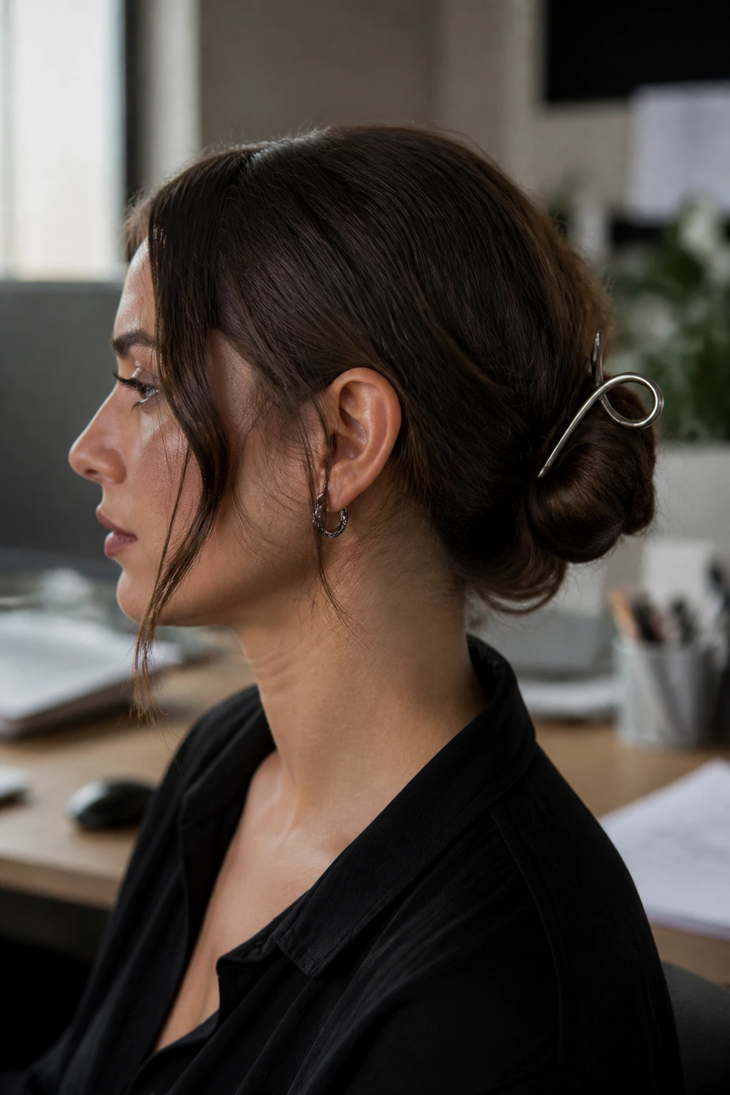 Close-up profile of a real woman with a low bun and metal hair accessory.
