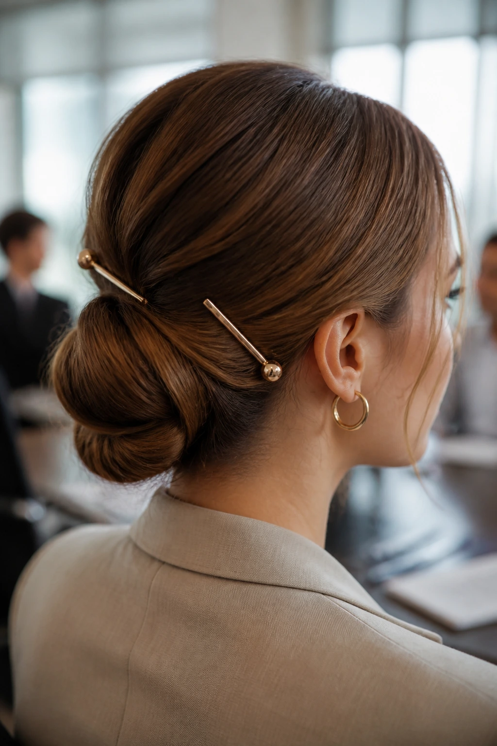 Real woman with a low bun accented by decorative pins in a professional setting
