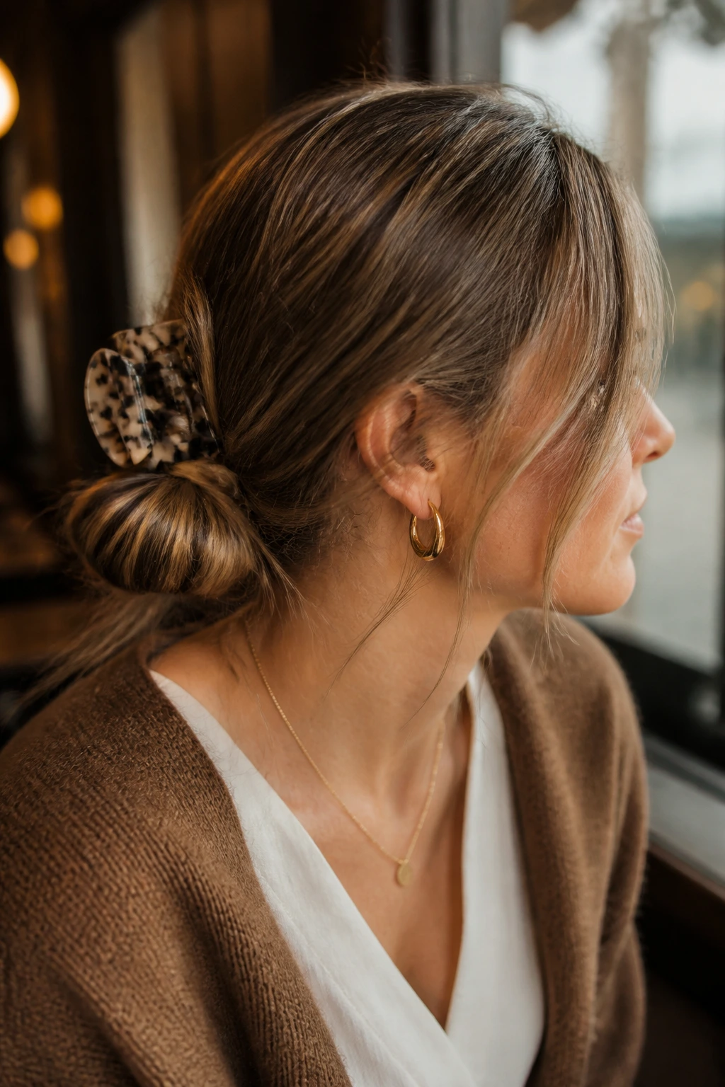 Portrait of a woman with a low messy bun and a large statement clip in warm indoor light