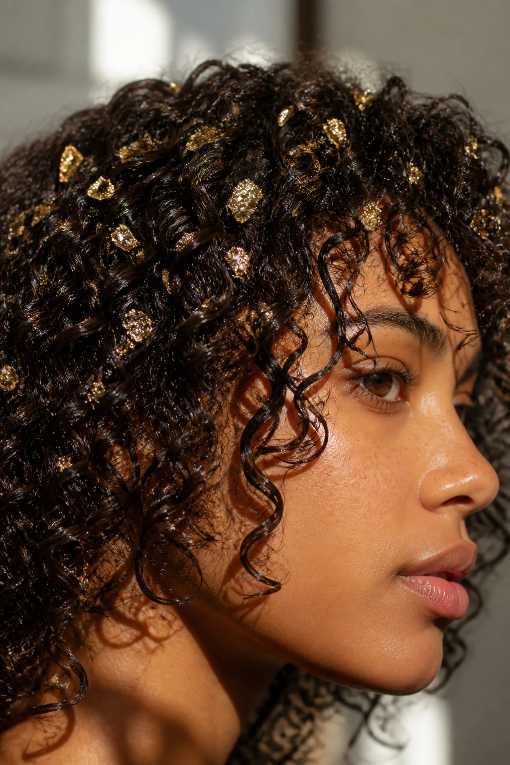 Curly hair with tiny gold leaf sprinkles on wet curls