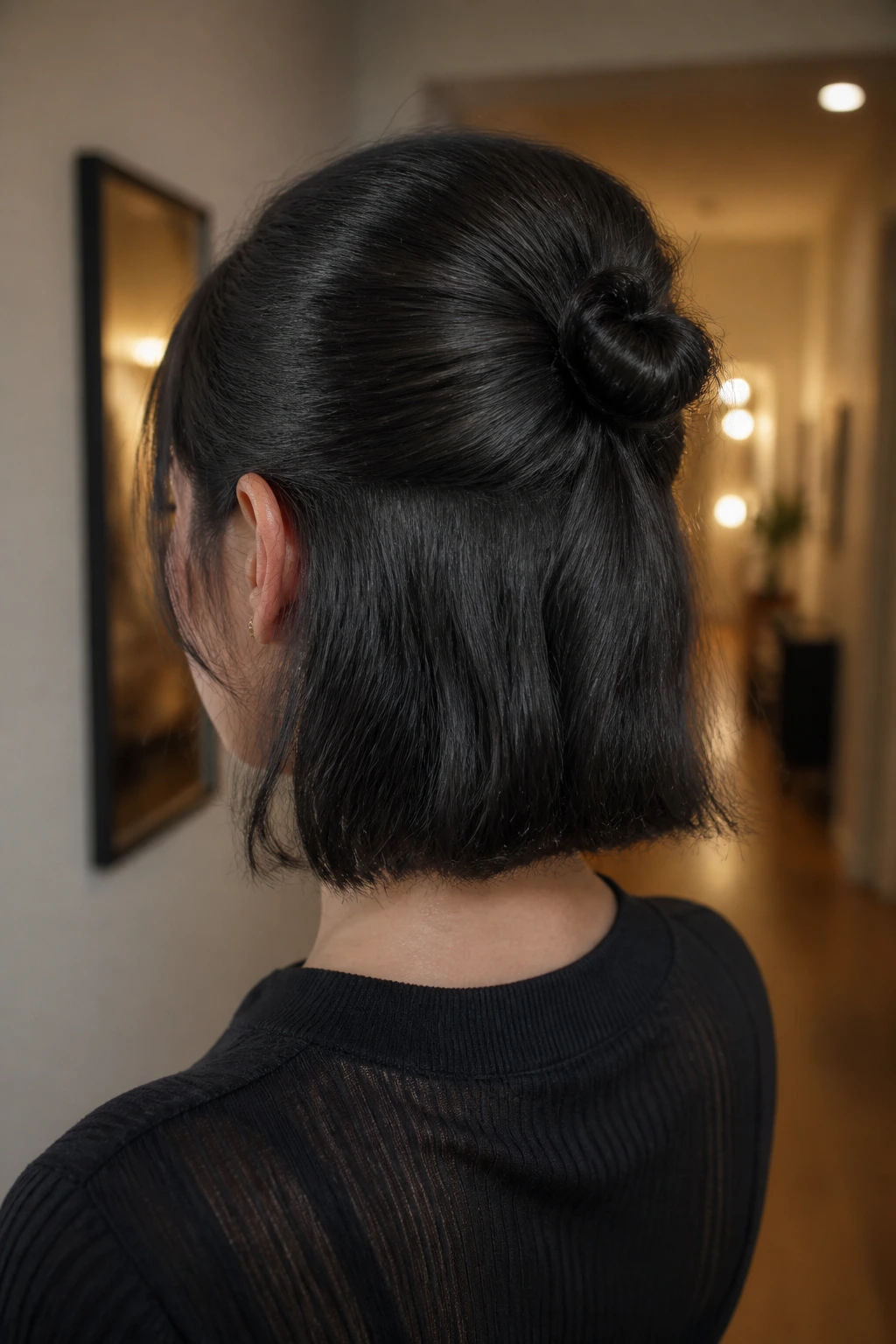 Rear view of a real person showing a tiny knot at the crown of slicked-back hair