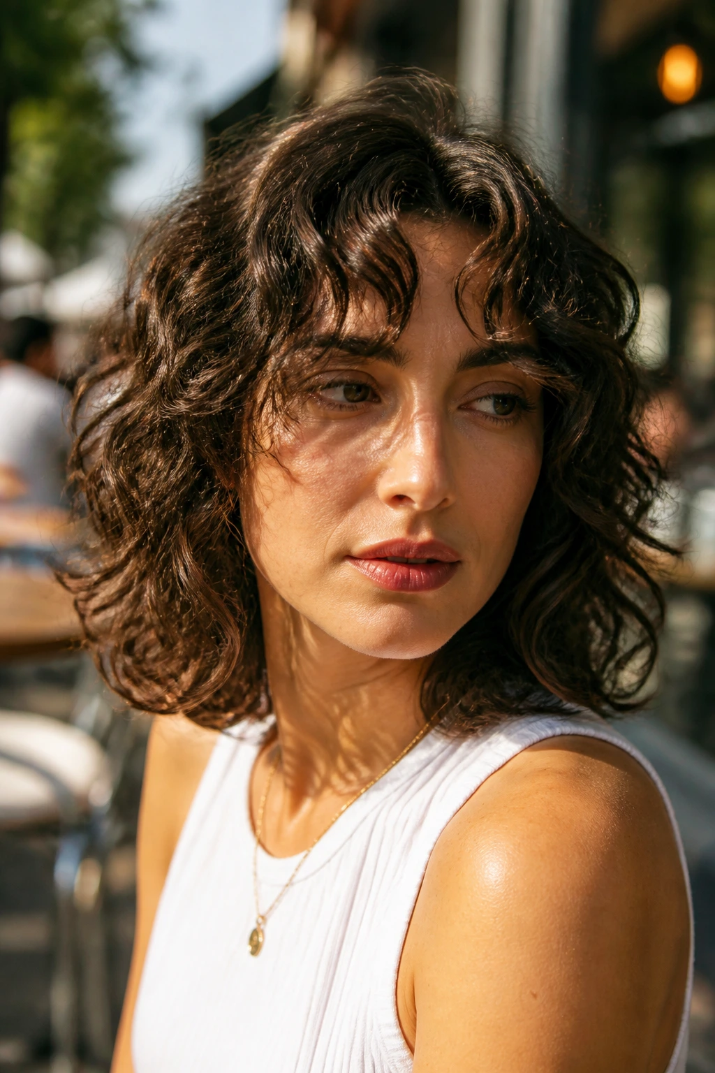 Close-up of a real woman with shoulder-length shag bob and wispy curtain bangs in sunlit backdrop.