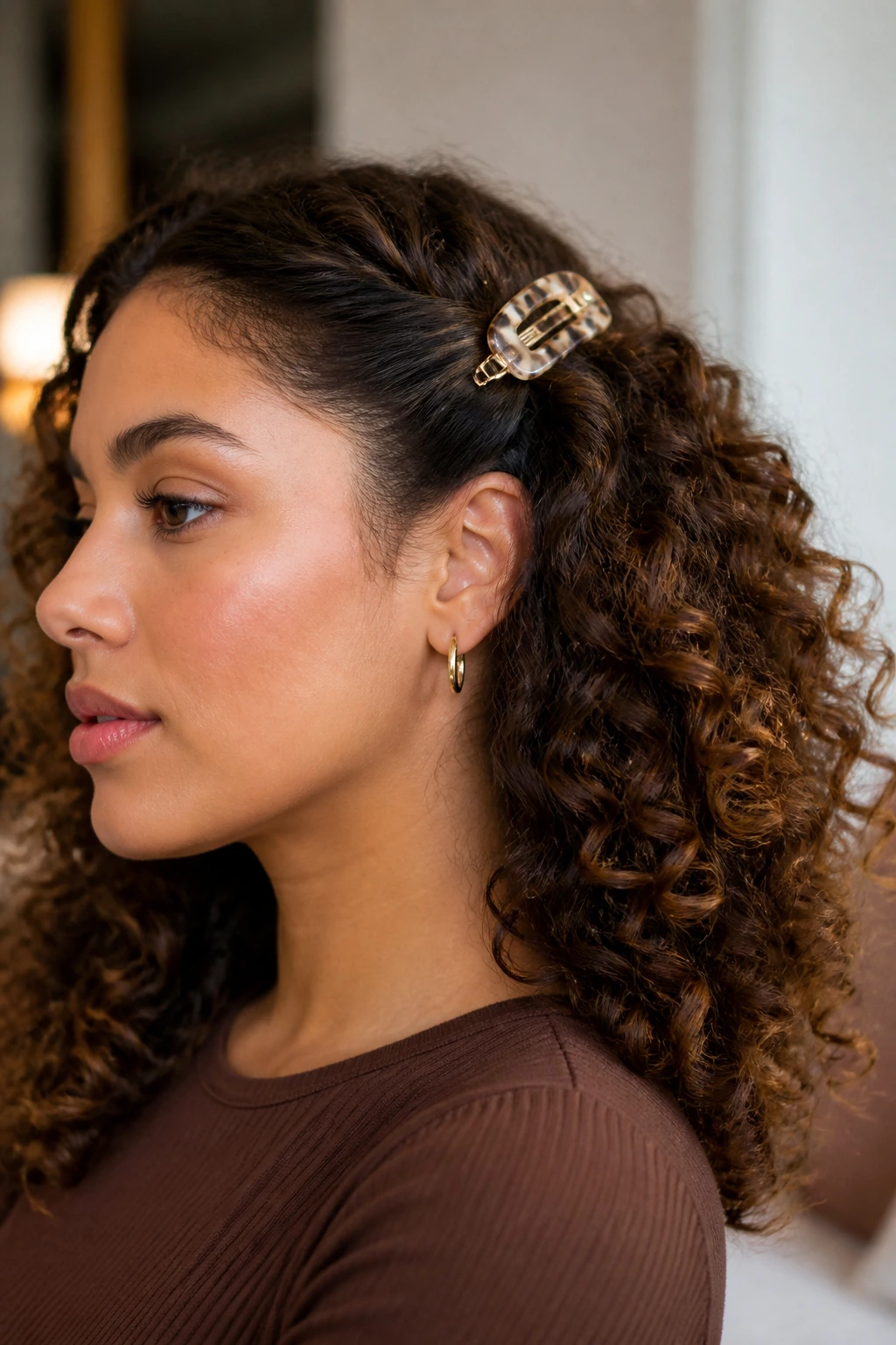 Close-up portrait of a real woman with a side twist secured by a decorative barrette near the ear.