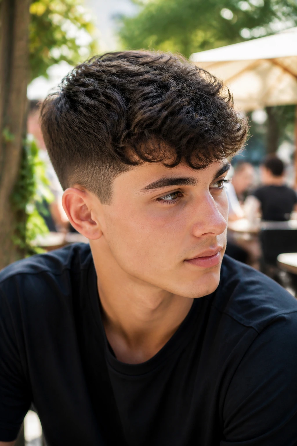 Close-up of a young man with a wavy crop hairstyle at a sunny cafe